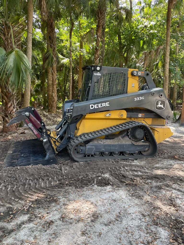 Skid-steer loader clearing land for a site preparation project by Trash Mania.